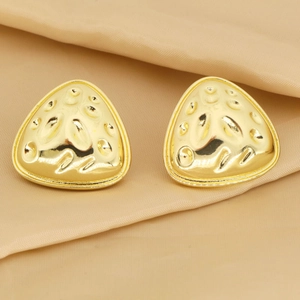 Detalle de pendientes triangulares dorados con textura única sobre fondo beige
