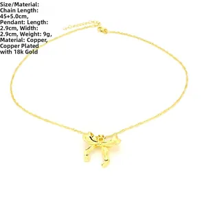 Detailed view of gold bow pendant necklace with 18k gold plating on white background