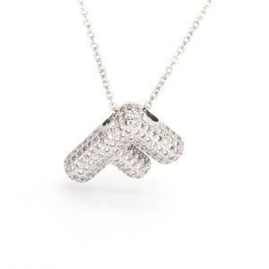 Vista macro de collar con colgante de inicial plateado y pavé de circonitas brillantes