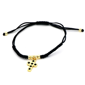 Detailed view of black woven rope bracelet with gold cross pendant and zircon inlay