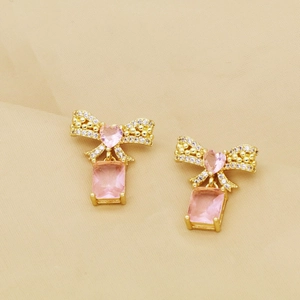 Details von goldenen Schleifenohrringen mit rosa Herzsteinen und Kristallanhängern