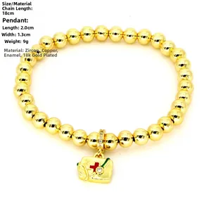 Macro detail of 18k gold plated medical kit charm with red cross and zircon on beaded bracelet
