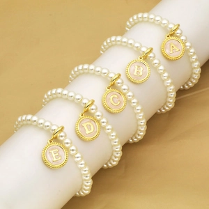 Detail of faux pearl bracelets with gold initial pendants A to E on elegant display