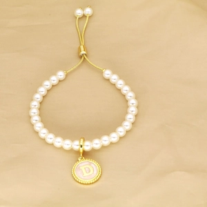 Detail of pearl bracelet featuring an adjustable gold closure and pink letter D pendant