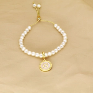 Detailed view of adjustable pearl bracelet featuring a gold round letter G pendant charm