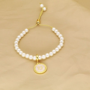 Detail of pearl bracelet featuring adjustable gold slide clasp and pink enamel letter H charm