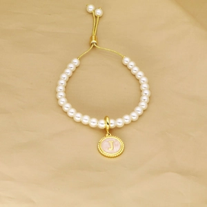 Detail of pearl bracelet featuring golden J letter pendant and adjustable pull clasp