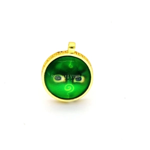 Macro shot of ethnic style round golden pendant with green eye pattern inlay and ornate frame