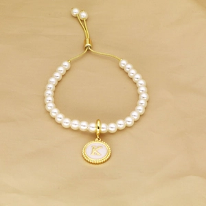 Detailed macro view of the gold K letter pendant on the adjustable pearl bracelet