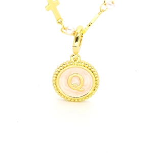 Détail du collier doré avec pendentif lettre Q, émail rose, perles et petite croix