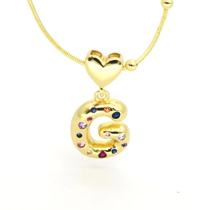 Macro detail of puffy letter G pendant with colorful cubic zirconia in 18k gold plating