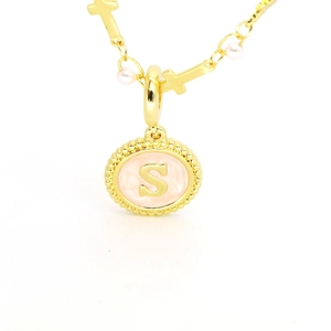 Détail macro du pendentif lettre S doré avec émail rose et petite perle délicate