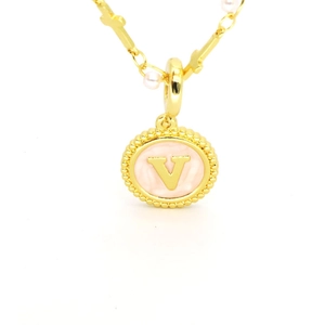 Détail du pendentif lettre V dorée avec émail rose et collier à maillons perles