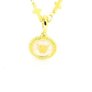 Détail d'un pendentif doré en émail rose avec la lettre W sur une chaîne à croix