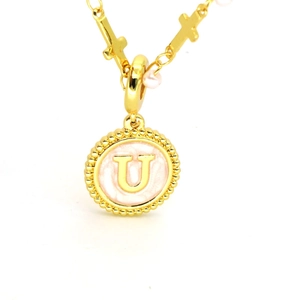 Détail du pendentif lettre U dorée avec émail rose et chaîne de croix élégante