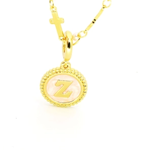 Détail du collier doré avec pendentif lettre Z, breloque croix et perle blanche