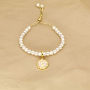 Adjustable pearl bracelet featuring a pink enamel letter S pendant and gold-tone chain