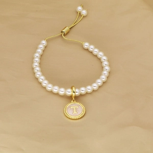 Detail view of pearl bracelet with golden letter T charm and adjustable drawstring closure
