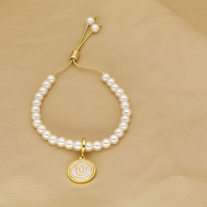 Detail showing letter U charm on pearl bead bracelet with golden adjustable chain link