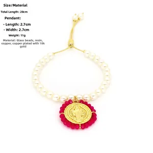 Détail du bracelet en perles avec médaille Saint-Benoît dorée et cadre en cristal rouge