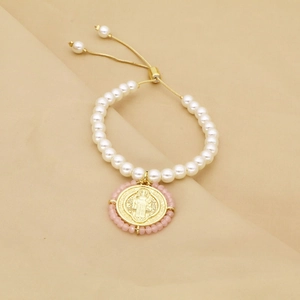 Détail du bracelet en perles avec un pendentif religieux doré et une chaîne réglable