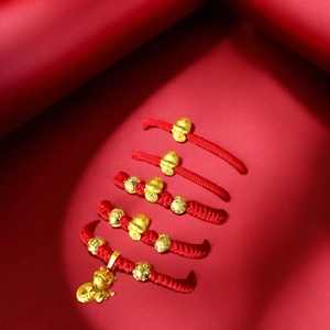 Macro shot of five red woven bracelets with golden snake charms and luck character