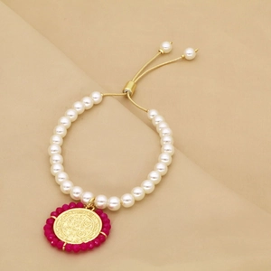 Détail d'un bracelet en perles avec pendentif doré et perles roses sur tissu doux