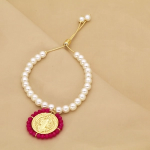 Détail de la médaille religieuse avec perles roses sur le bracelet en perles