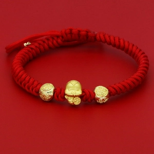 Macro view of a red woven zodiac rabbit bracelet with gold beads and Fu character