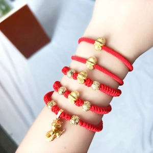 Detailed view of red woven bracelets with golden charms and lucky beads for women