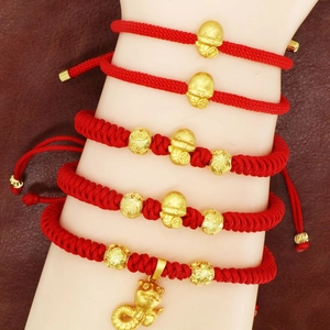 Detail of five handcrafted red braided bracelets with golden Chinese zodiac charms