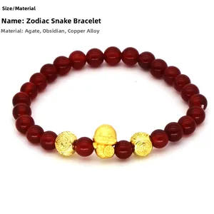 Macro view of red agate beads bracelet with a golden snake charm and fortune symbols