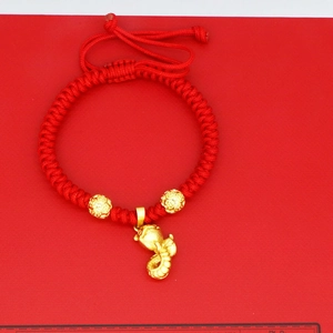 Macro view of hand-woven red string bracelet with gold zodiac snake and lucky beads