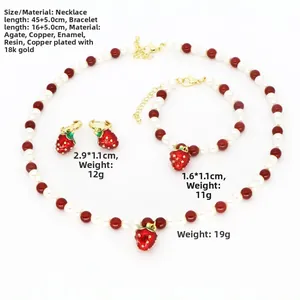 Détails d'une parure bijoux fraise avec perles rouges, agate et plaqué or 18 carats