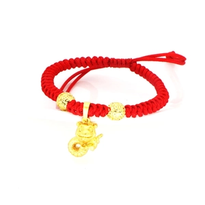 Close-up of handmade red braided bracelet with gold snake pendant and coin beads