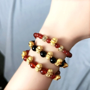 Close-up of triple stacked zodiac snake bracelets with red agate and black obsidian beads