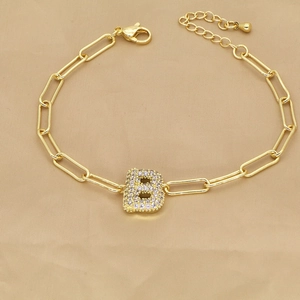 Detail of 18k gold paperclip chain bracelet featuring a zircon-encrusted letter B charm