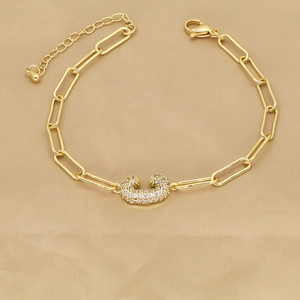 Detail of 18k gold paperclip chain bracelet with a pavé zircon letter C pendant