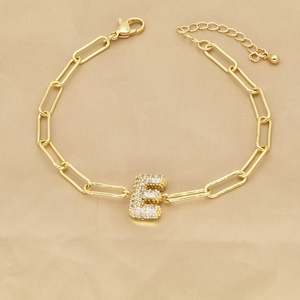 Detail of 18k gold paperclip chain bracelet with micro-paved zircon letter E pendant