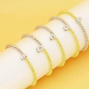 Detail of 18k gold plated beaded stretch bracelets with zircon alphabet bubble pendants