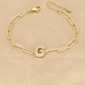 Detailed shot of 18k gold paperclip chain bracelet with zircon pavé letter G pendant