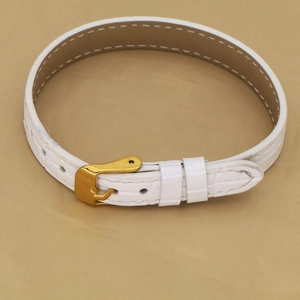 Detail of white crocodile pattern leather strap with golden metal buckle and adjustment holes