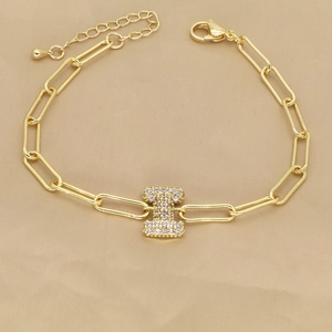 Detail of 18k gold paperclip chain bracelet with a zircon-encrusted letter I charm
