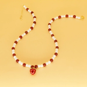Détail d'un collier de perles fraise avec perles blanches et rouges et fermoir doré