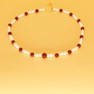 Détail du collier de perles avec fraises rouges et fermoir mousqueton doré