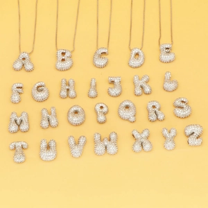 Collection of 26 gold bubble letters with pavé zircon stones on yellow background