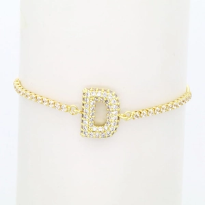 Macro view of gold-plated bracelet featuring a zircon-encrusted capital letter D pendant