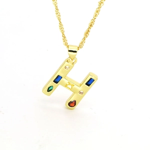 Macro detail of gold-plated H-letter pendant with colorful zircon stones on rope chain