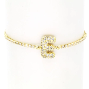 Macro view of gold-plated letter E pendant with crystal pavé on tennis bracelet chain