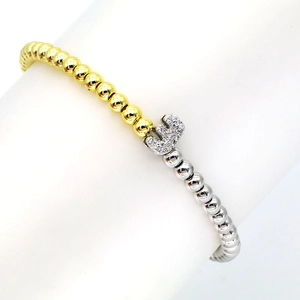 Detailed close-up of mixed gold and silver beads with a zircon-set letter E charm